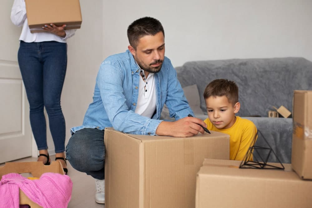 A man clearly labelling boxes with room names and contents