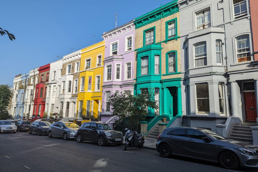 Street in Notting Hill, London with brightly painted terrace houses and parked cars