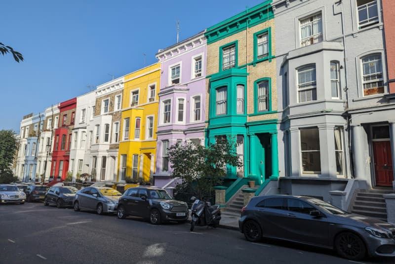 Street in Notting Hill, London with brightly painted terrace houses and parked cars
