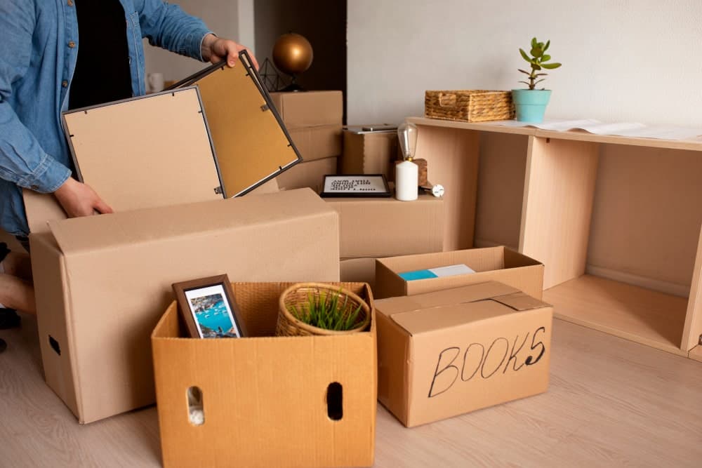 man packing pictures and books into cardboard boxes