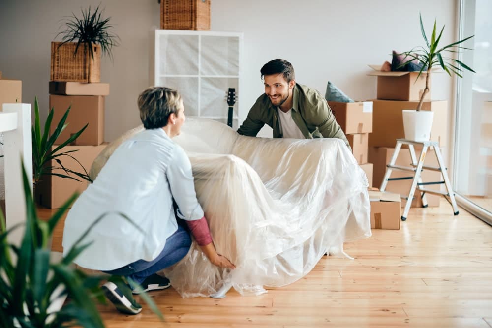 Couple lifting a sofa in their house during a DIY move